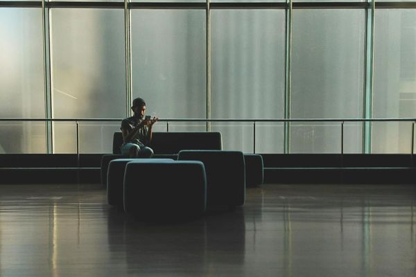 Person sitting calmly by a large window in a minimalist interior.